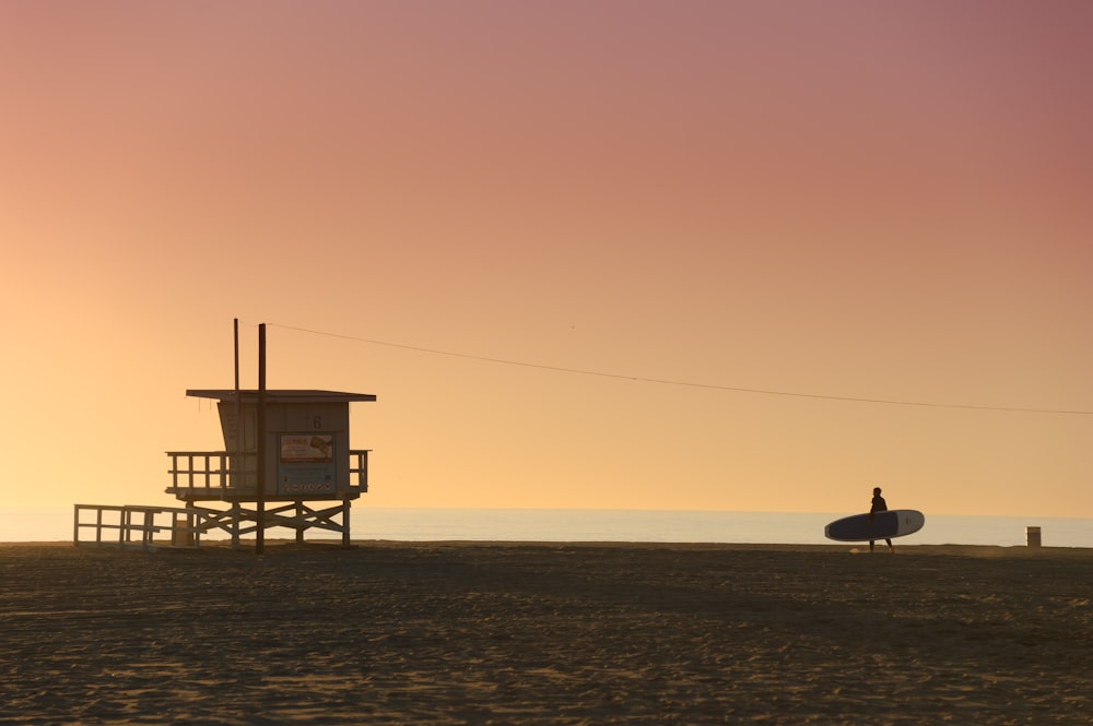 silhouette of bird on wooden lifeguard house during sunset