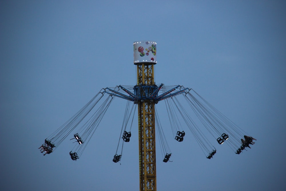 people riding on yellow and blue ferris wheel during daytime