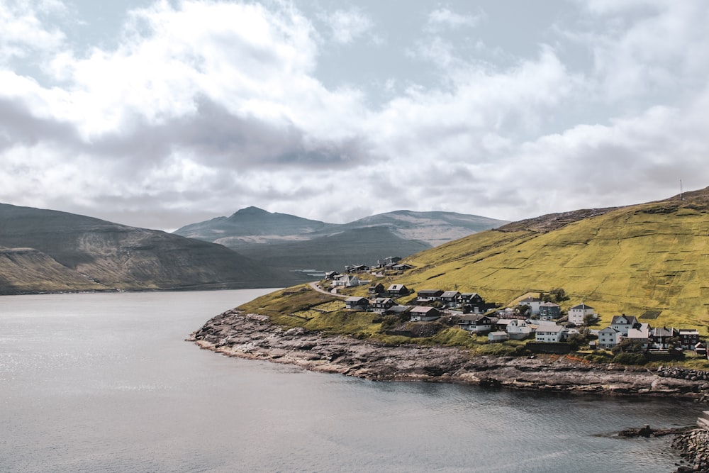 green and brown mountain beside body of water under white clouds during daytime