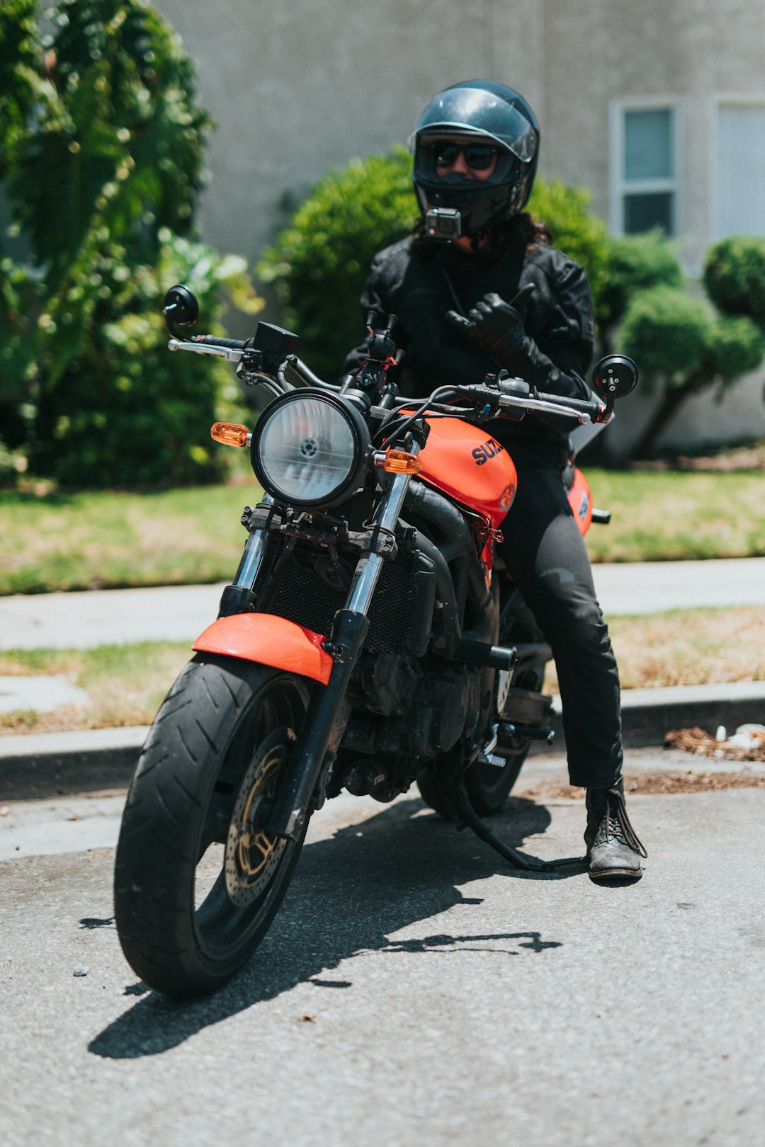 man in black leather jacket riding orange and black motorcycle during daytime