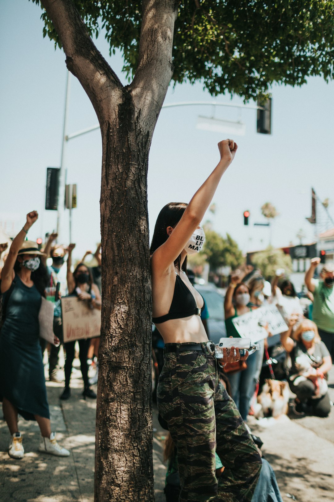 woman in black brassiere and black and brown camouflage pants raising her hands