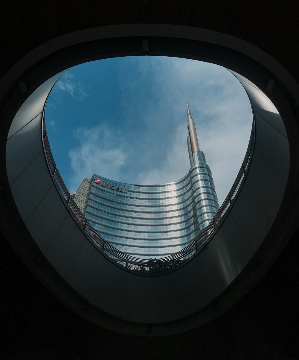 vista del ojo de los gusanos del edificio de hormigón gris bajo el cielo nublado soleado azul y blanco durante