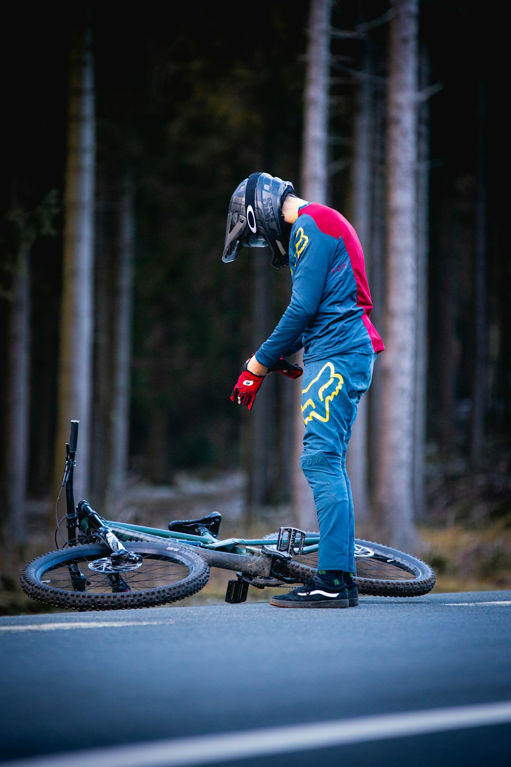 man in red jacket and blue pants riding black bicycle