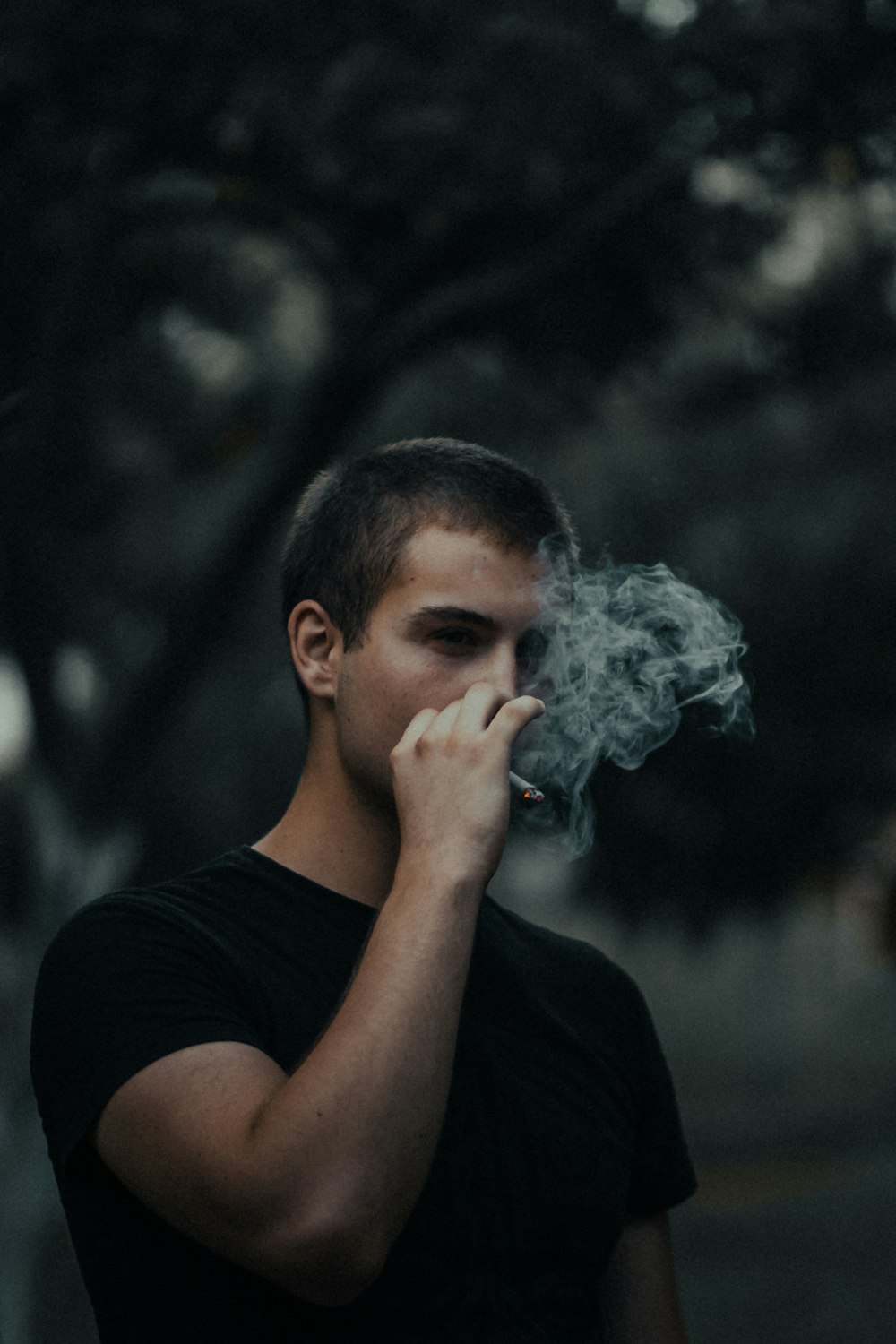 hombre en camiseta negra de cuello redondo fumando