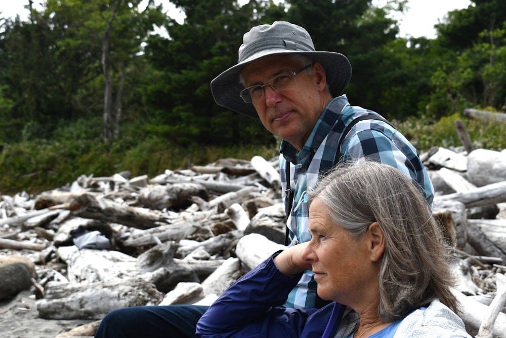 man and woman sitting on rock during daytime