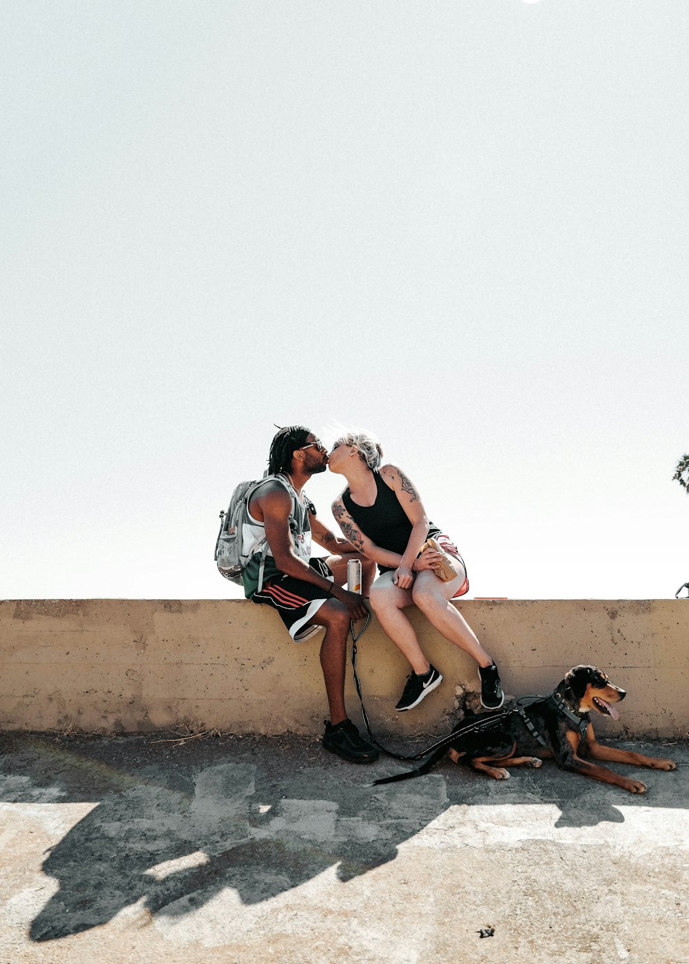 3 women sitting on brown concrete wall during daytime