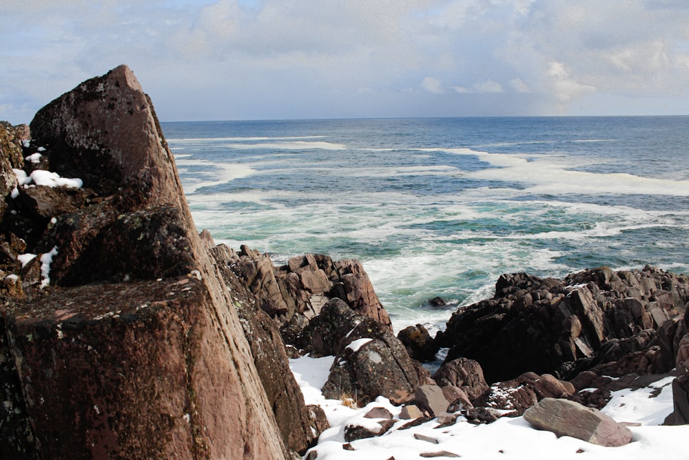 brown rocky mountain beside sea during daytime