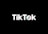 A minimalist logo featuring the word TikTok in a bold, white font centered on a black background. The 'o' in TikTok is stylized with a design resembling a musical note, incorporating subtle blue and red hues.
