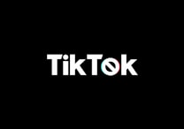 A minimalist logo featuring the word TikTok in a bold, white font centered on a black background. The 'o' in TikTok is stylized with a design resembling a musical note, incorporating subtle blue and red hues.