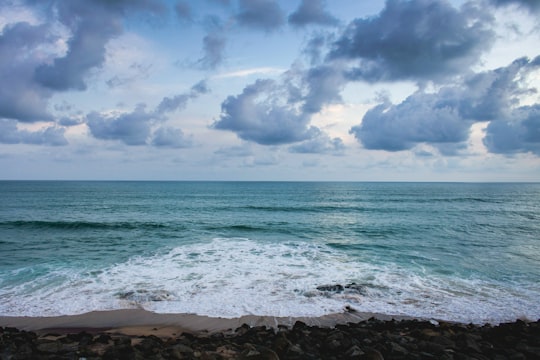 sea waves crashing on shore under blue and white cloudy sky during daytime in Kanyakumari India