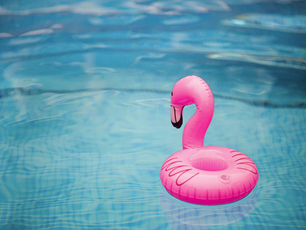 A vibrant flamingo pool float bobbing gently on a bright blue sunny pool.