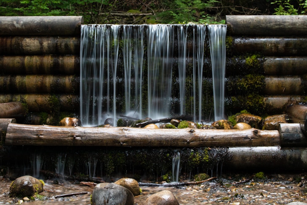 roches brunes sur rondin de bois brun près des chutes d’eau