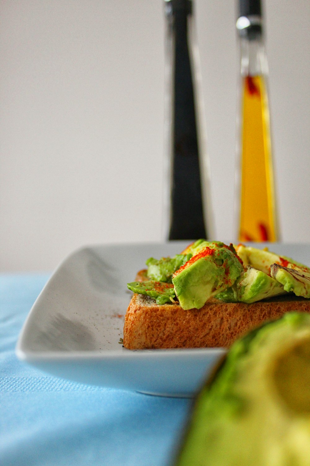 a white plate topped with a sandwich next to an avocado