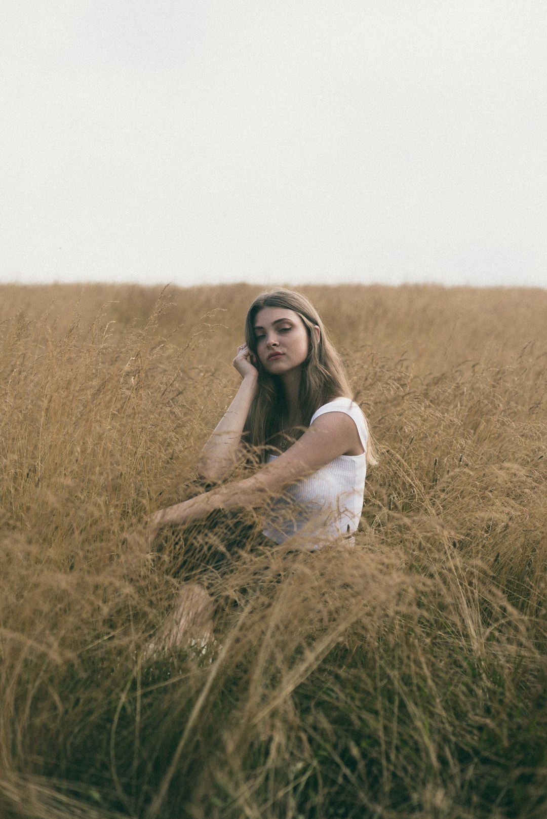 woman in white dress sitting on brown grass field during daytime