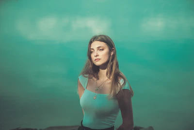 A serene portrait of Divya Mishra smiling softly against a pastel blue background.