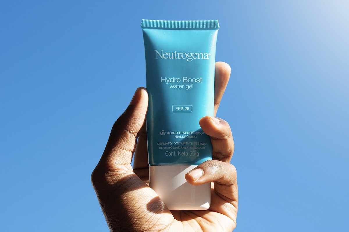 A person holding an unbranded skincare tube in one hand