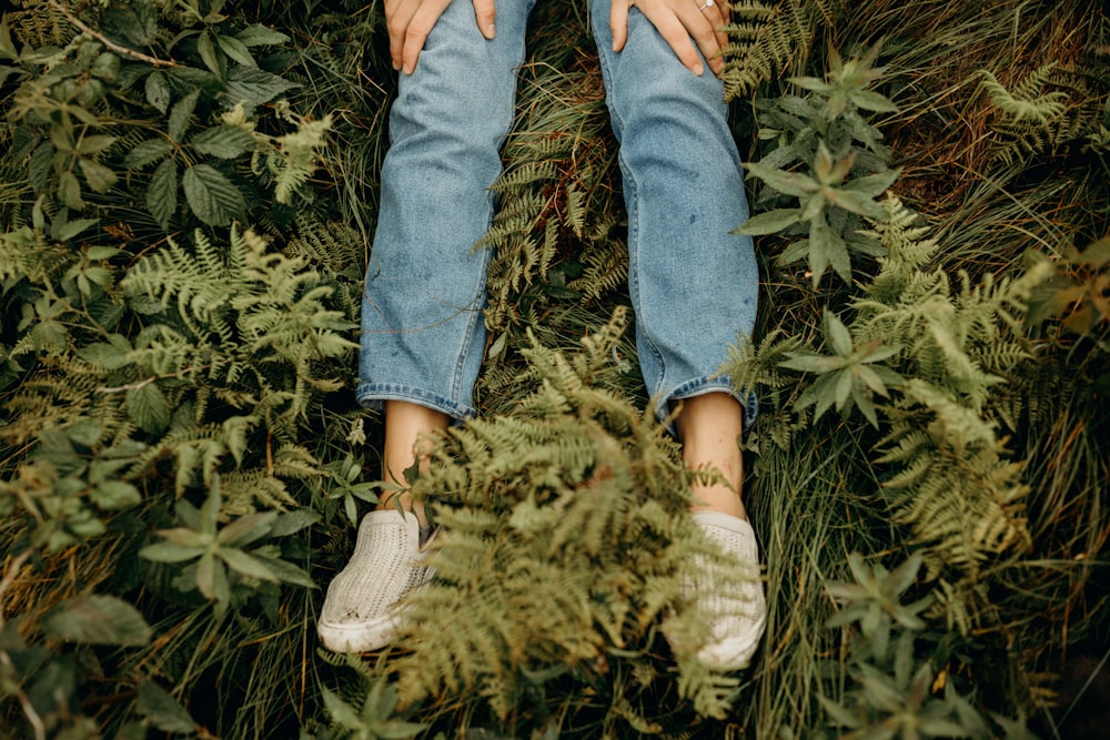 personne en jean bleu et baskets blanches