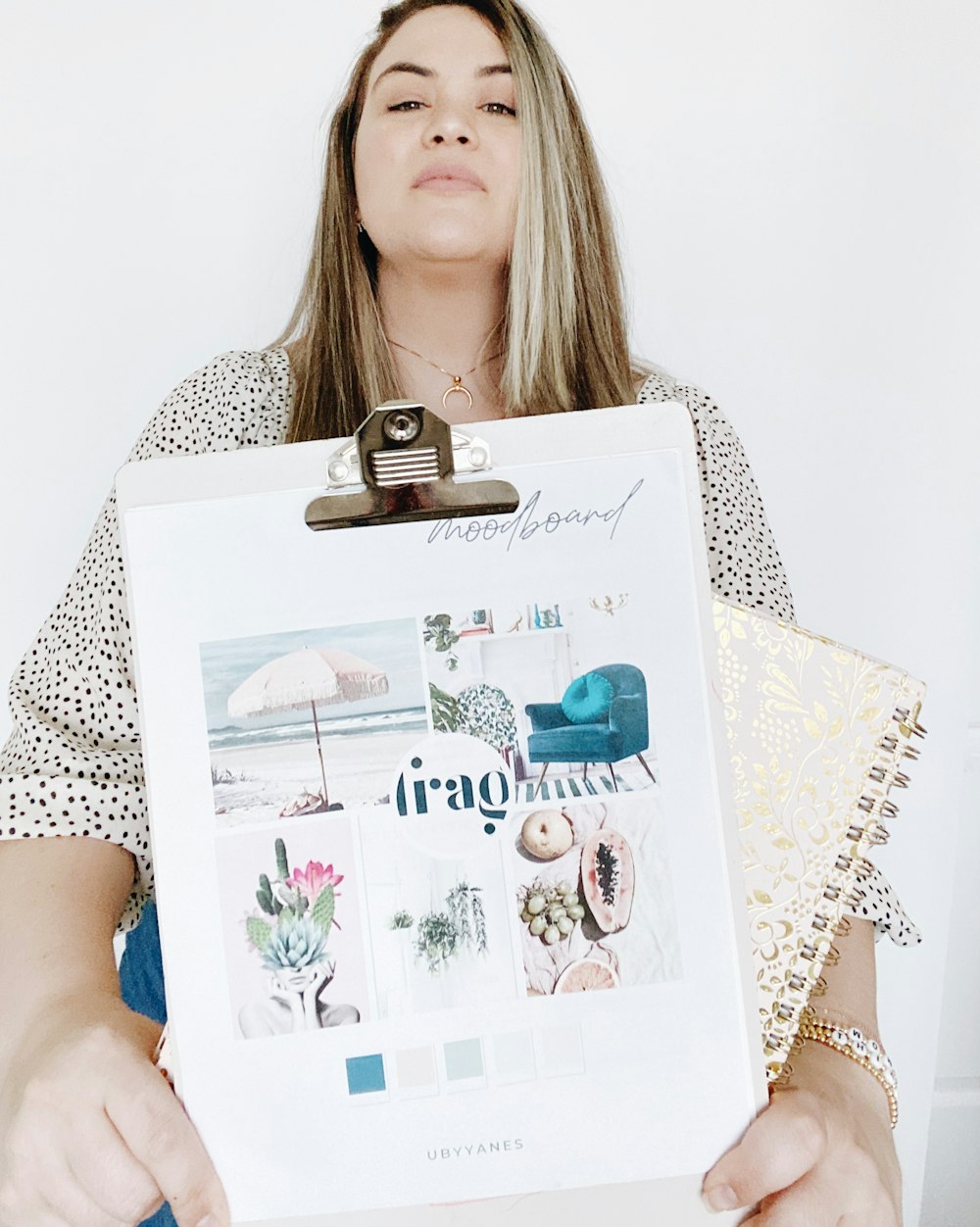 woman in white and black polka dot shirt holding white and pink floral greeting card