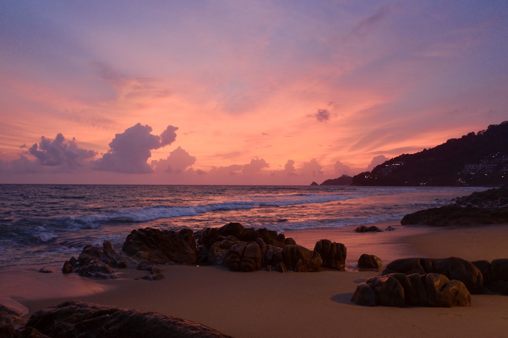 Rocas marrones en la orilla del mar durante la puesta de sol