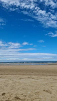 Visitors enjoying a peaceful walk along a quiet, pristine beach with soft white sand.