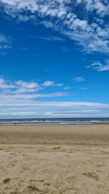 Tourists enjoying a peaceful beach walk along Bali’s blue ocean shore.