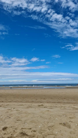 Visitors enjoying a peaceful walk along a quiet, pristine beach with soft white sand.