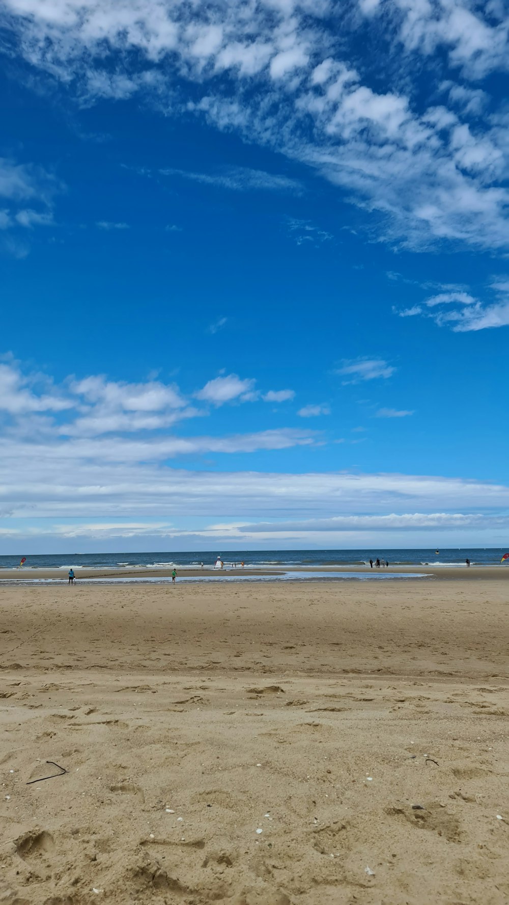 brown sand near body of water under blue sky during daytime