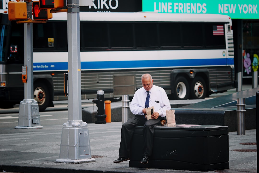 man in white dress shirt and black pants sitting on black luggage bag