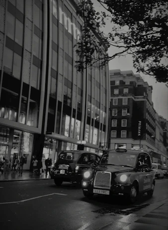 A sleek black LEVC TX cab waiting elegantly by the curb on a rainy London evening.