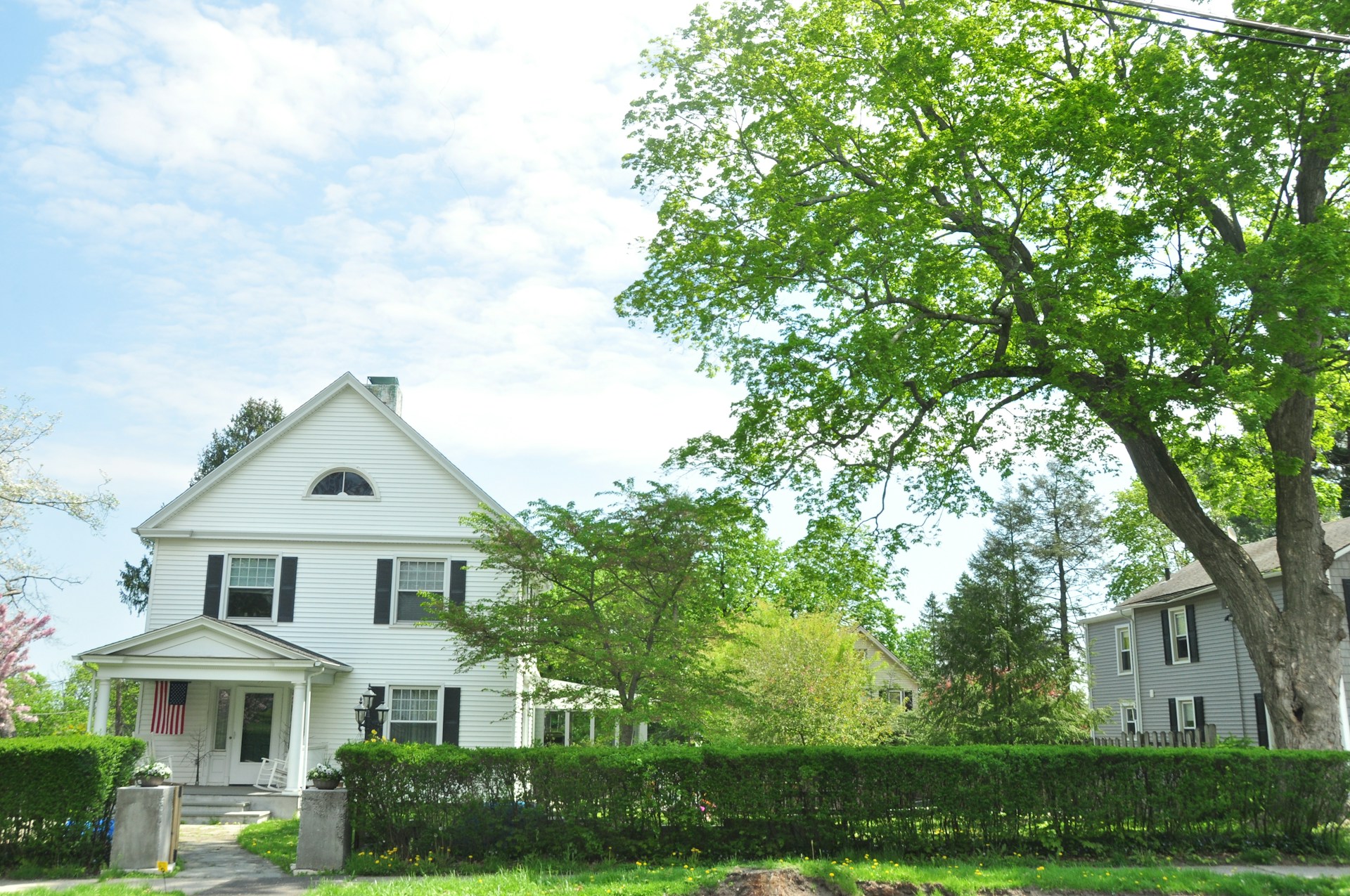 white and gray house near green trees under white clouds during daytime