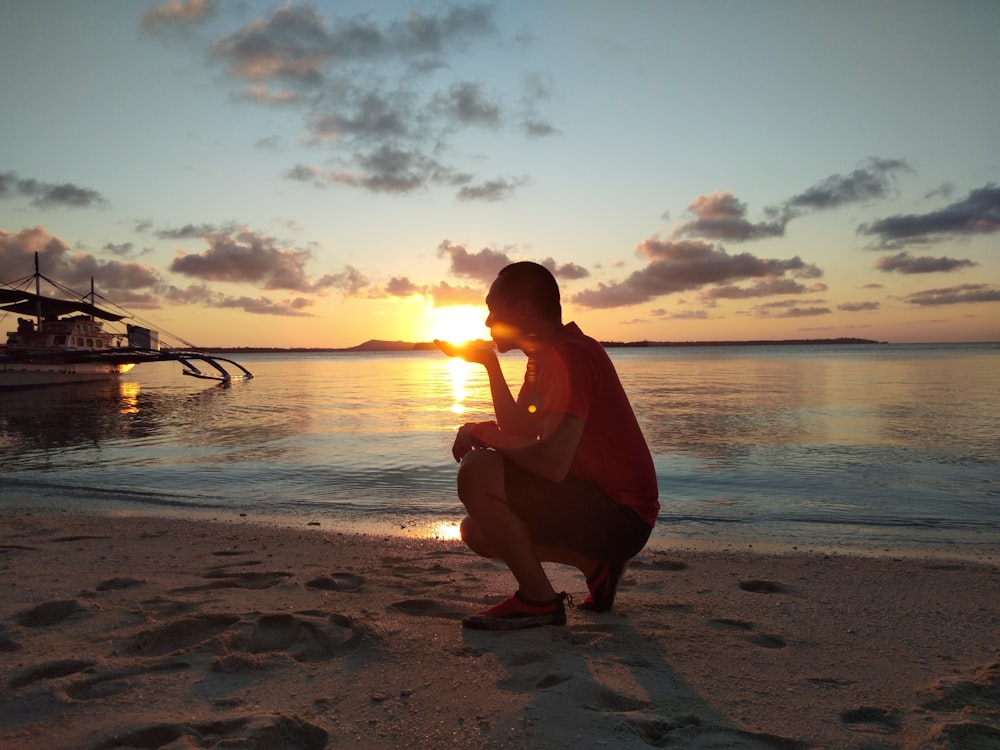 Frau in rotem Kleid sitzt bei Sonnenuntergang am Strand