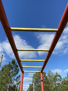 Brightly painted monkey bars with children climbing together under a clear blue sky.
