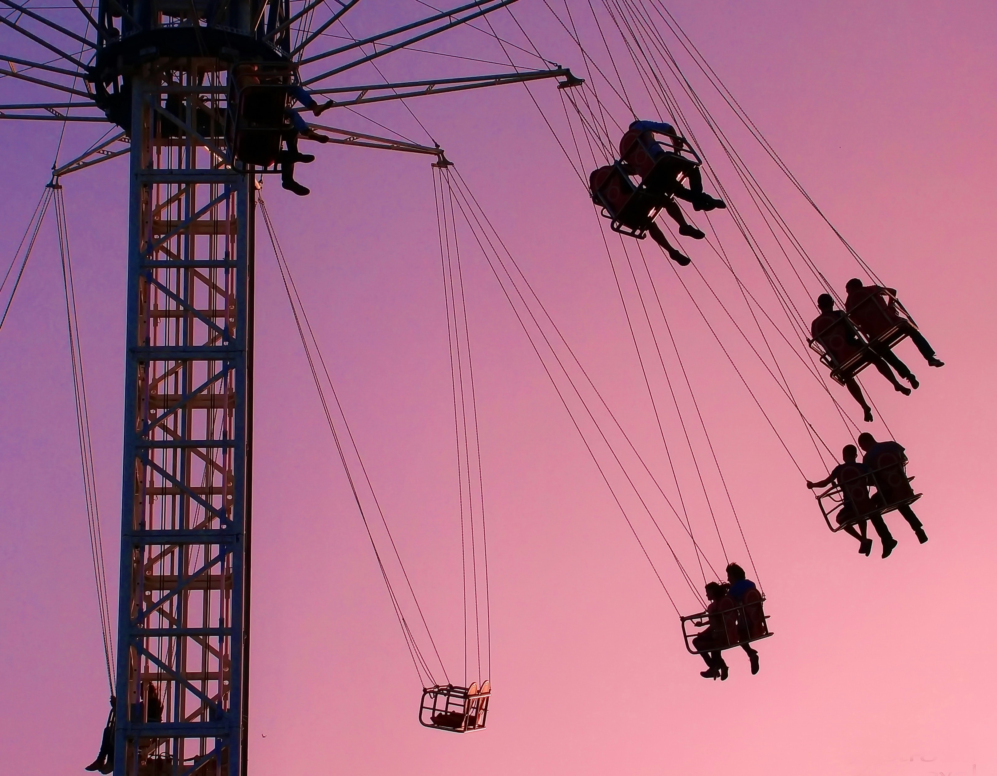 people riding on cable cars during daytime, Circle of happiness.</p><p>Against the background of the evening sky, vacationers fly on a carousel in an amusement park.