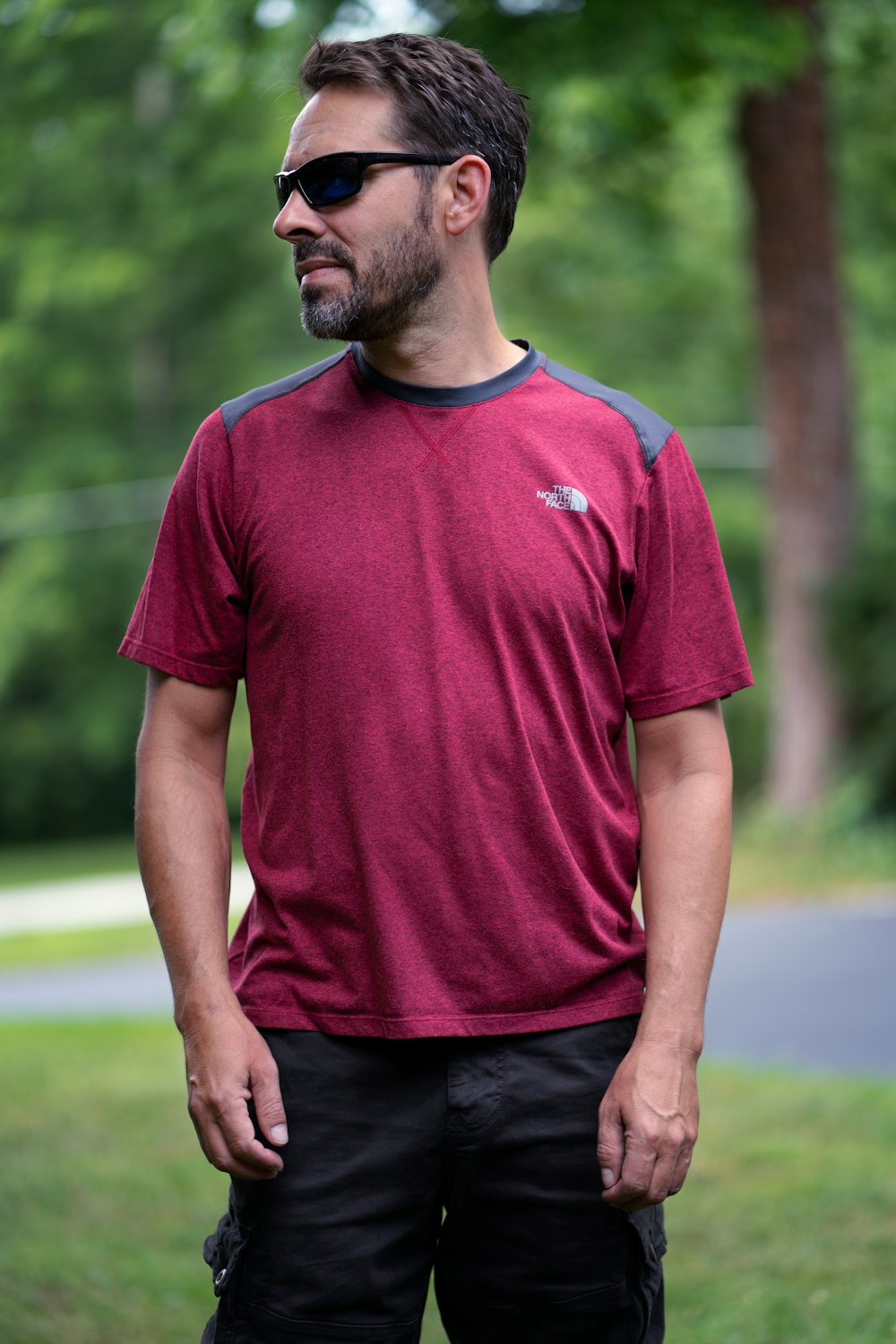man in red nike crew neck t-shirt standing on green grass field during daytime