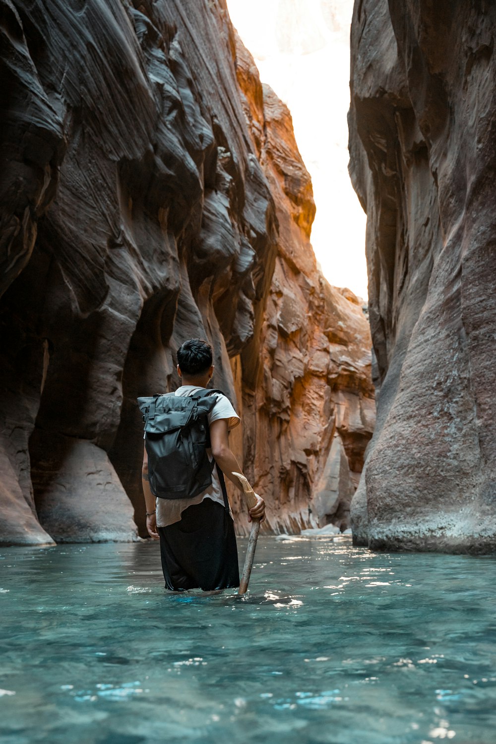 man in black jacket and black pants standing in front of brown rock formation during daytime