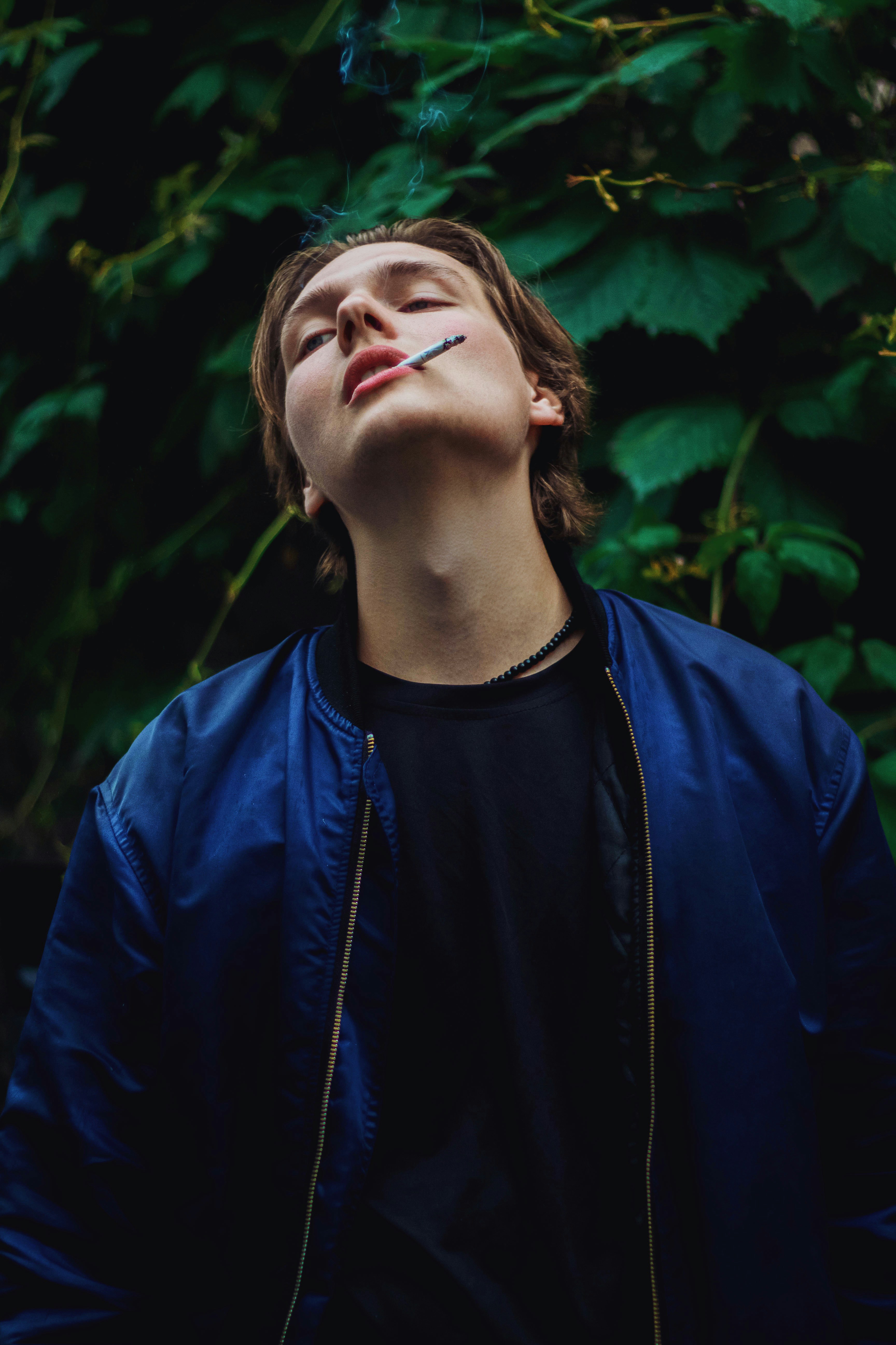 man in blue crew neck shirt standing near green leaves