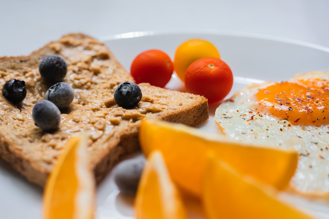 sliced bread with sliced orange and blue berries on white ceramic plate