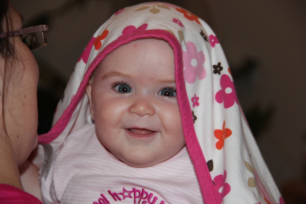 baby in pink and white floral blanket