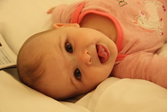baby in pink shirt lying on bed