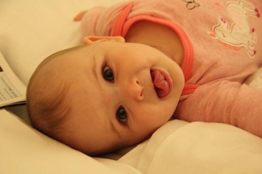 baby in pink shirt lying on bed