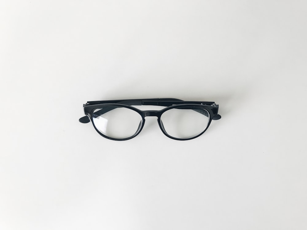 black framed eyeglasses on white surface