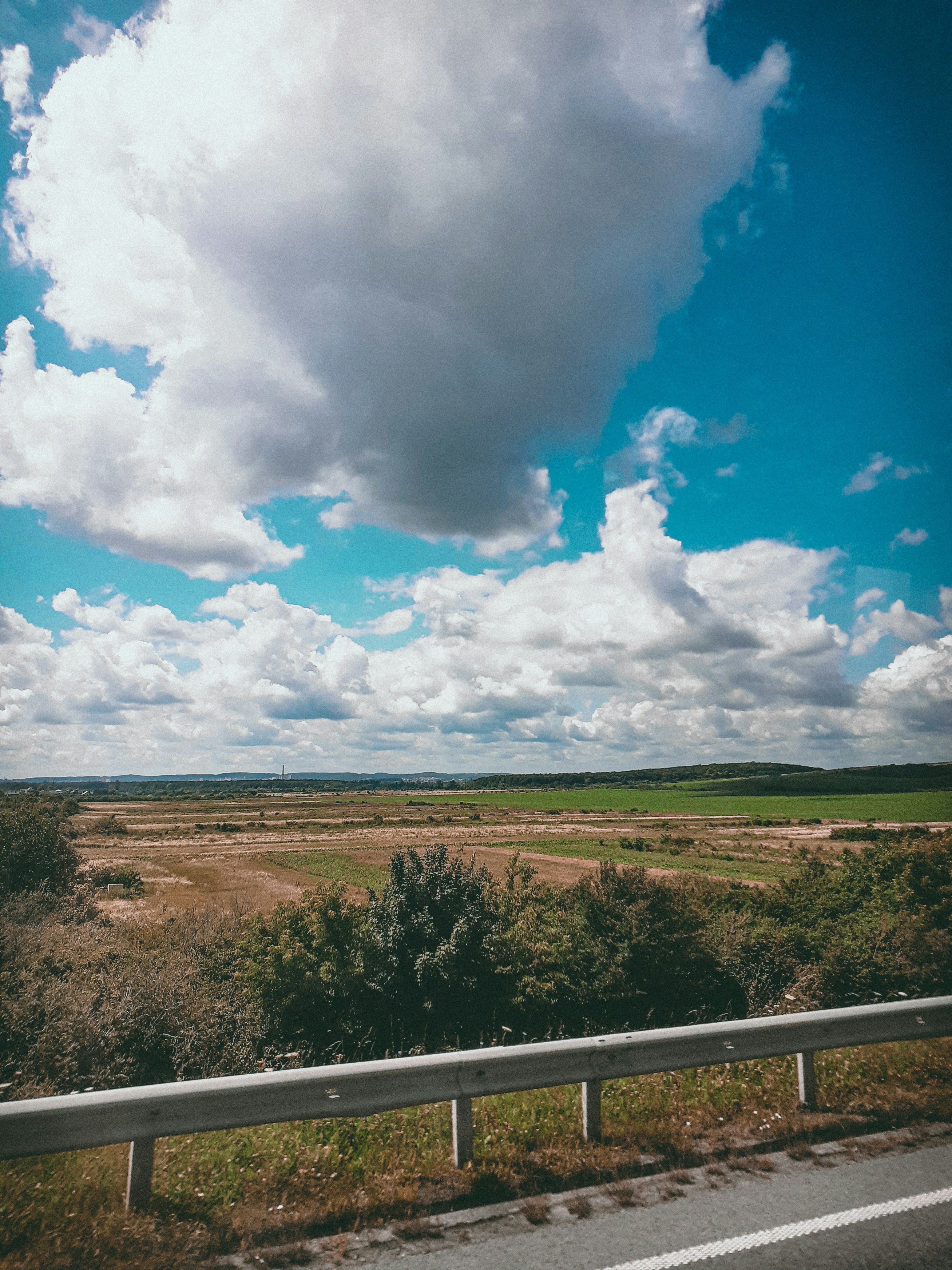 green grass field under blue sky and white clouds during daytime