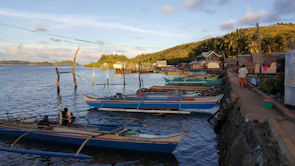 Traditional wooden boats docked along the calm water of a Sabah fishing village