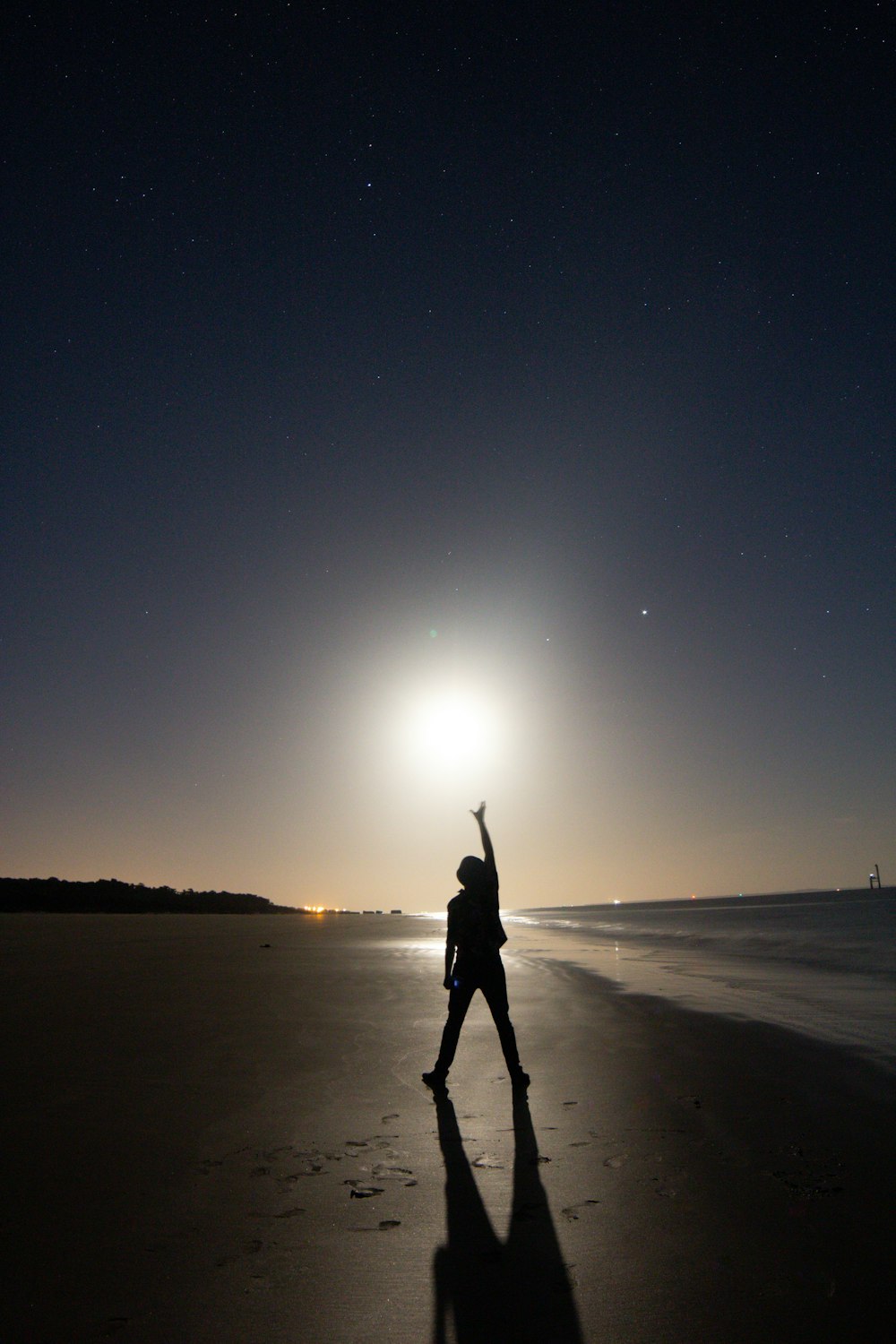 uma pessoa em pé em uma praia à noite