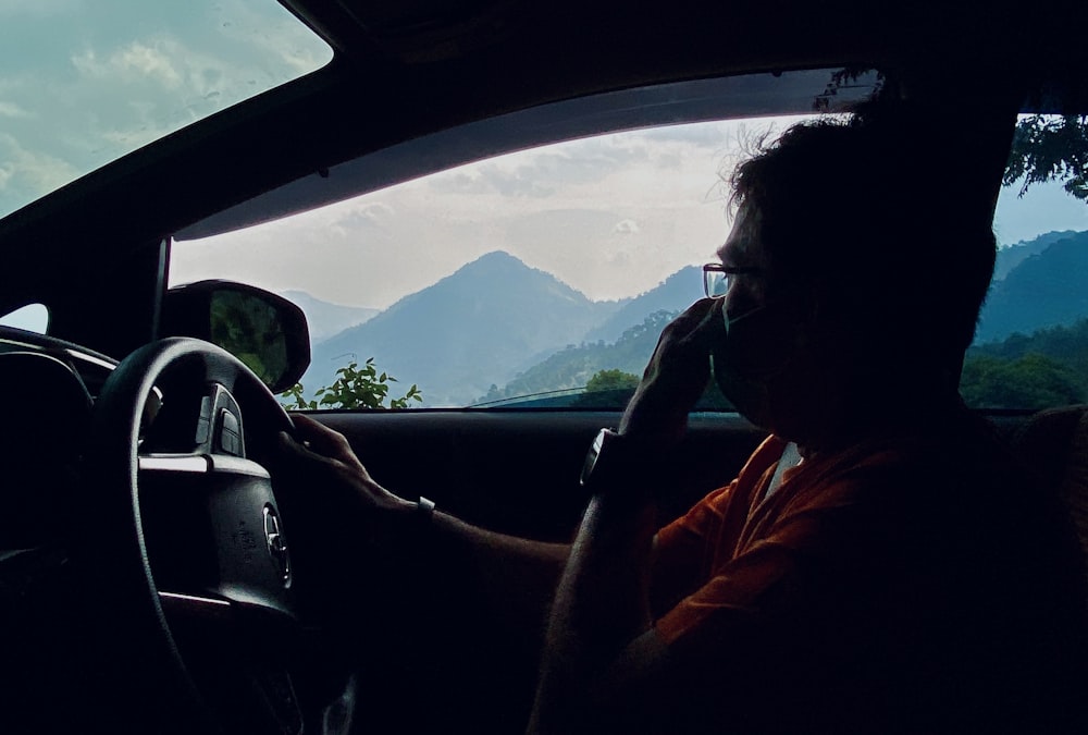 man in orange jacket driving car during daytime