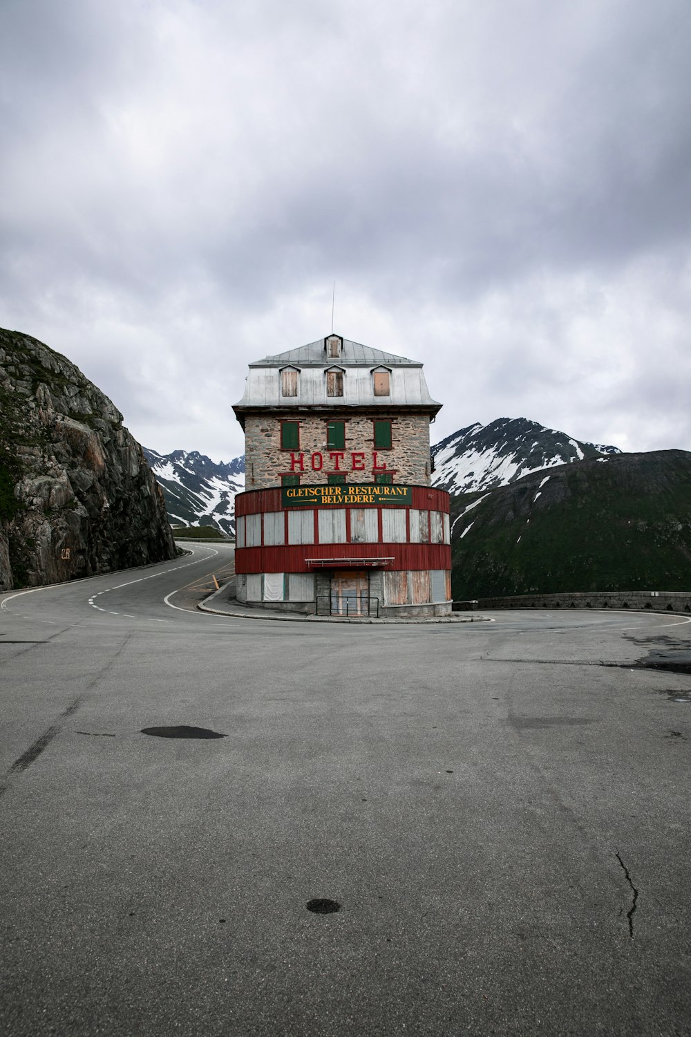 red and white concrete building near mountain under white clouds during daytime