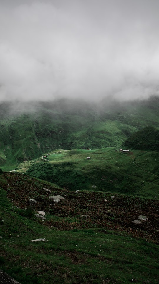 green grass field under white clouds during daytime in Furka Pass Switzerland