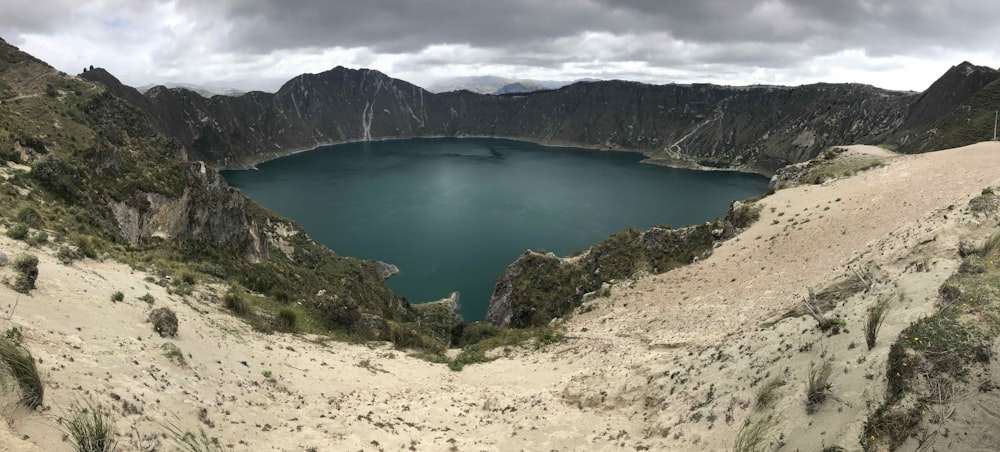 green lake surrounded by mountains during daytime