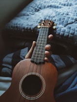 person holding brown acoustic guitar