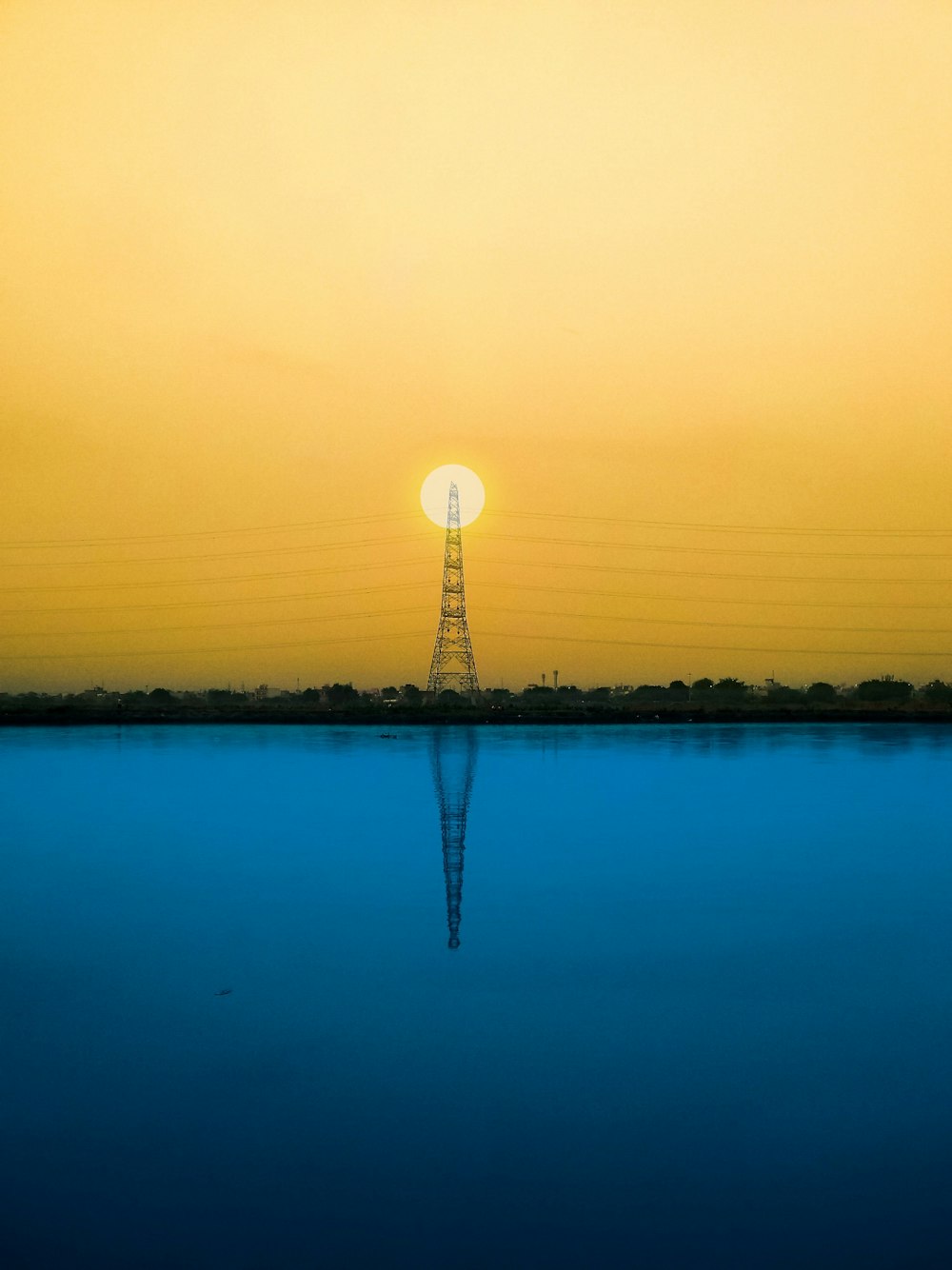 silhouette of trees and body of water during sunset